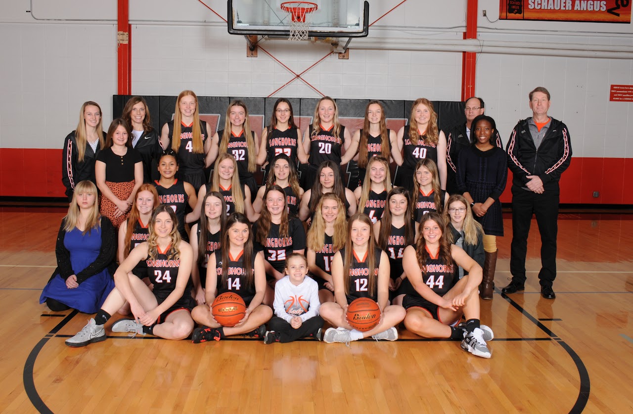 Group team photo in gym in front of basketball hoop